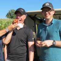 Three golfers posing for picture hotdog in face